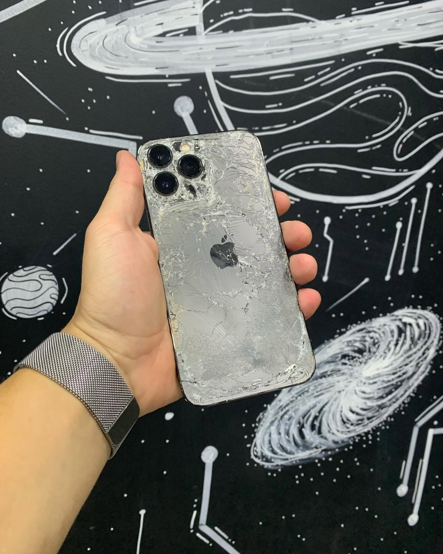 iPhone 12 Pro grafite com a traseira completamente estilhaçada